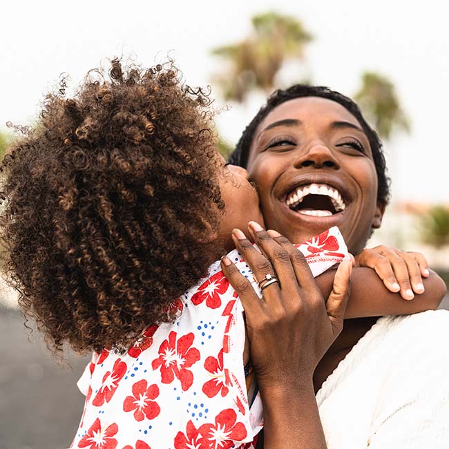A girl hugging her mother in the park while they smile after receiving family dentistry from Upland Laser Dental Center